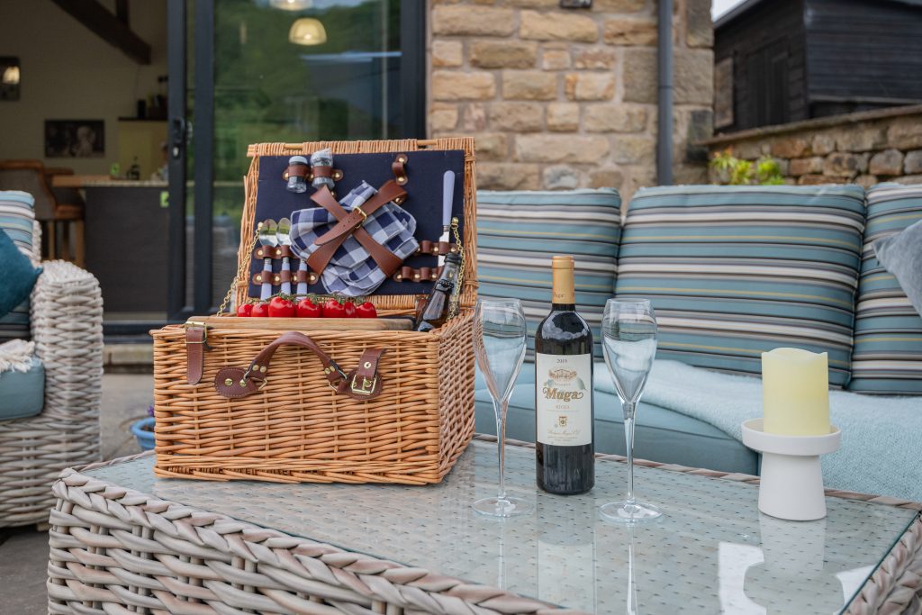  cozy patio scene showcasing a wicker basket with wine and a bottle.